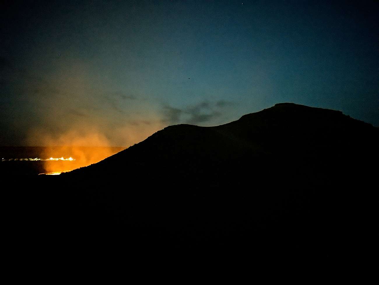 The Gates of Hell (Darwaza, Turkmenistan) - at night, glowing light from behind the hill